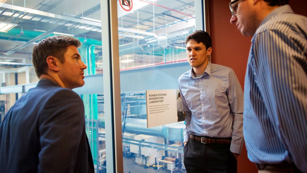 Three men looking out over a laboratory