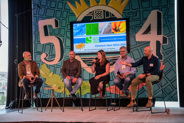 At an event, five people sit on stools during a panel discussion.